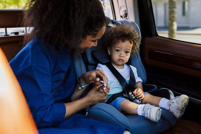 Woman holding hand of little boy in a car seat