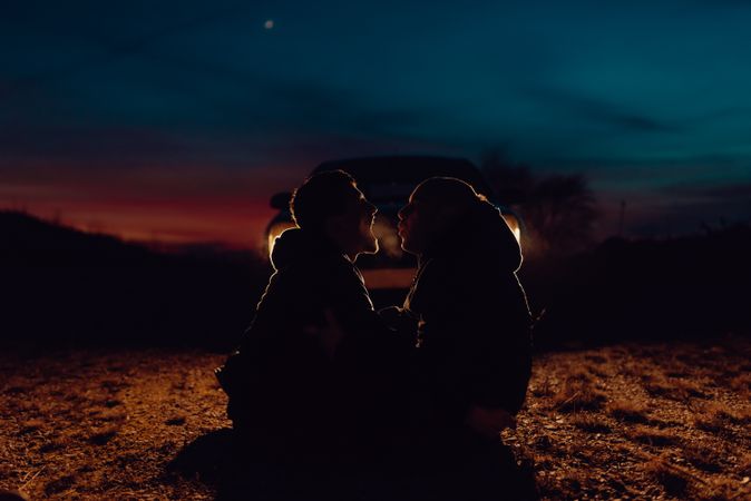 Men hugging and sitting on ground on field at night