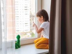 Toddler boy sits with green dragon or dinosaur