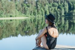 Young female sitting on pier on nature