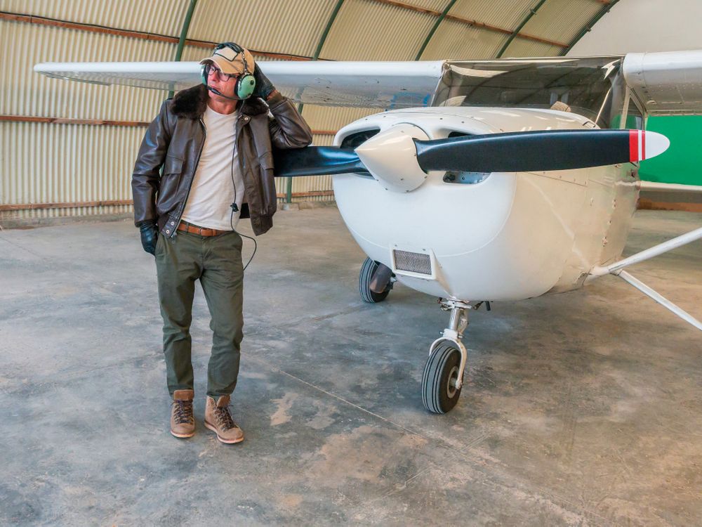 Confident pilot beside retro plane in hangar