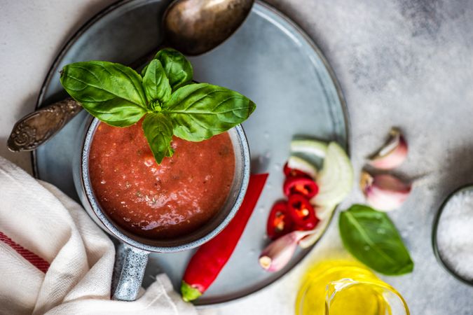 Top view of cup of gazpacho soup with basil, garlic, pepper and olive oil
