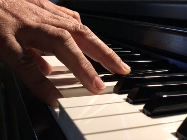 Persons hand playing piano
