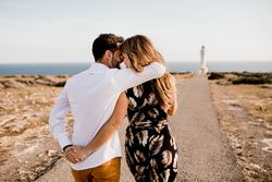 Smiling lovers cuddling on path to sea