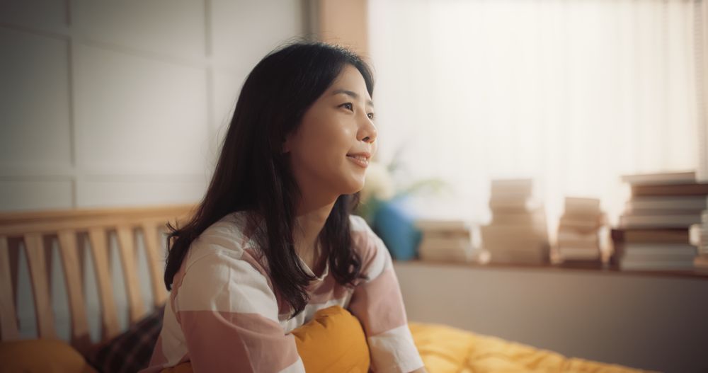 Portrait of Korean Woman Waking up in the Morning, Doing some Stretching, Sun Shines From the Apartment Window into Bedroom.