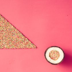 Coconut with sprinkles on pink background