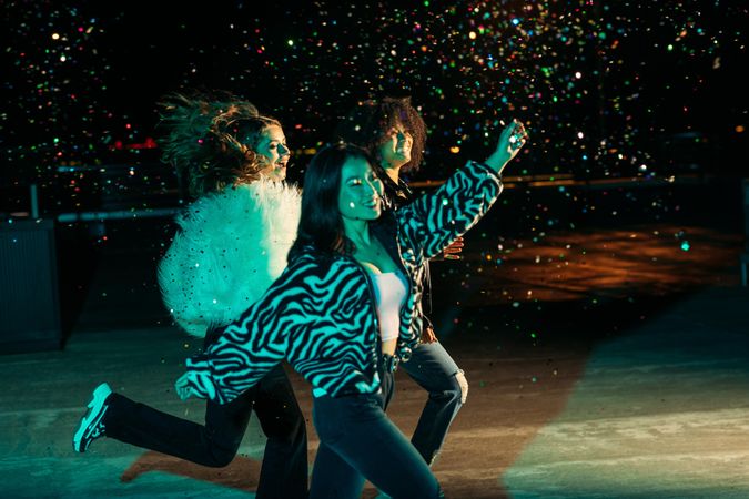 Three stylish woman celebrating outdoors with confetti