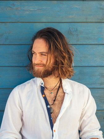 Cheerful guy sitting near blue wall