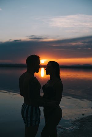 Couple hugging on beach of lake at sunset