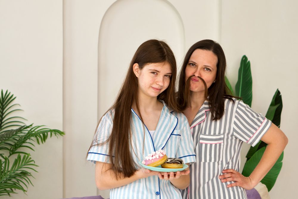 Mother and daughter making funny faces in striped pajamas.