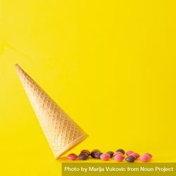 Upside down ice cream cone with candy on yellow background 5woxv5