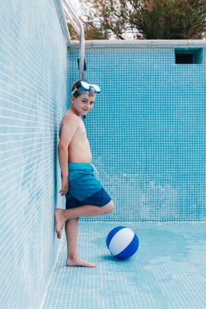 Boy with ball standing in empty pool
