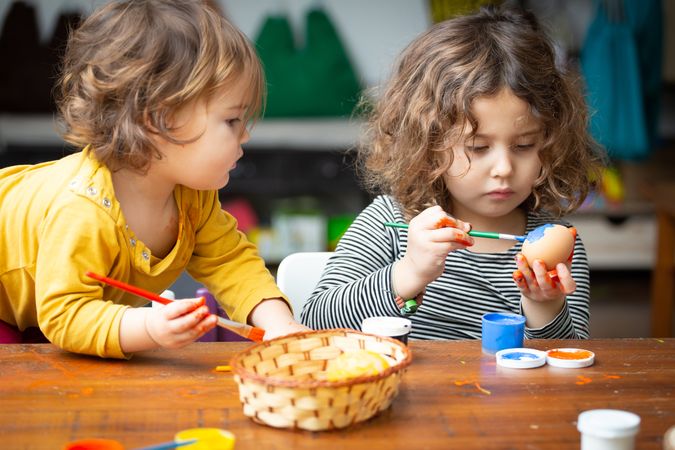 Sisters painting Easter eggs at home