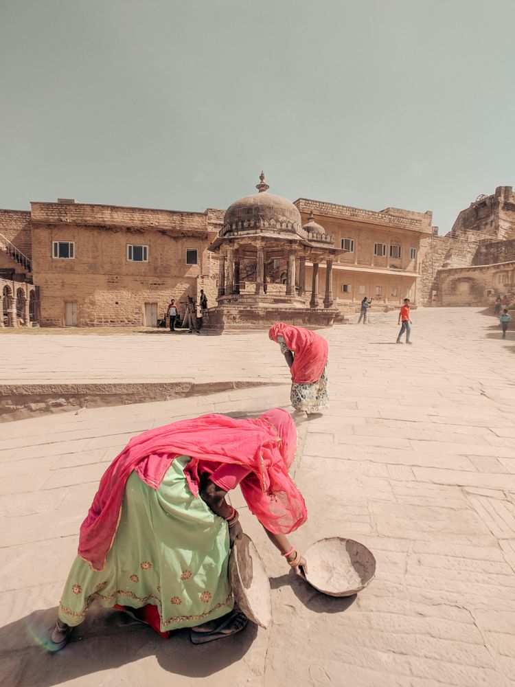 Two Indian women beside an old brown building in India
