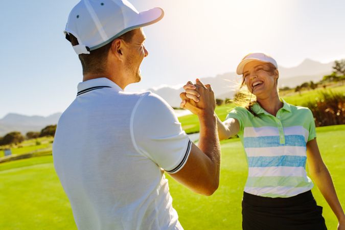Smiling couple ending round of golf with hand shake