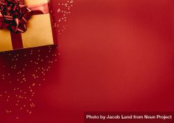 Flat lay of golden colored gift box with star confetti on red background 0gOJj0
