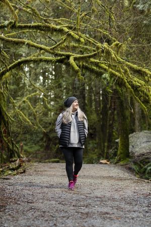 Older woman happily walking on a forest trail