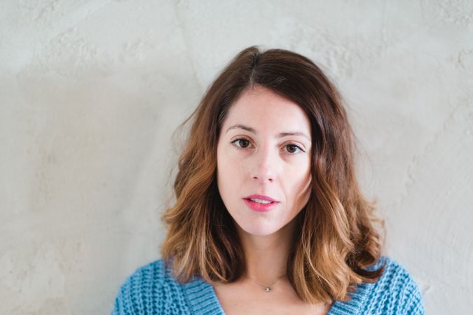 Charming woman in sweater near wall