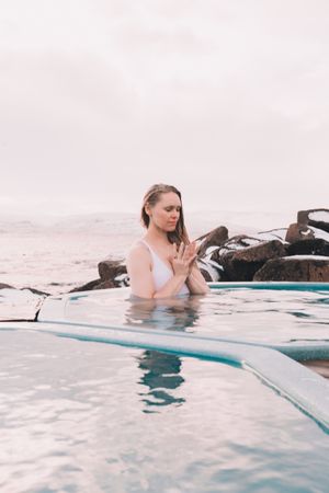Woman sitting in pool near stones