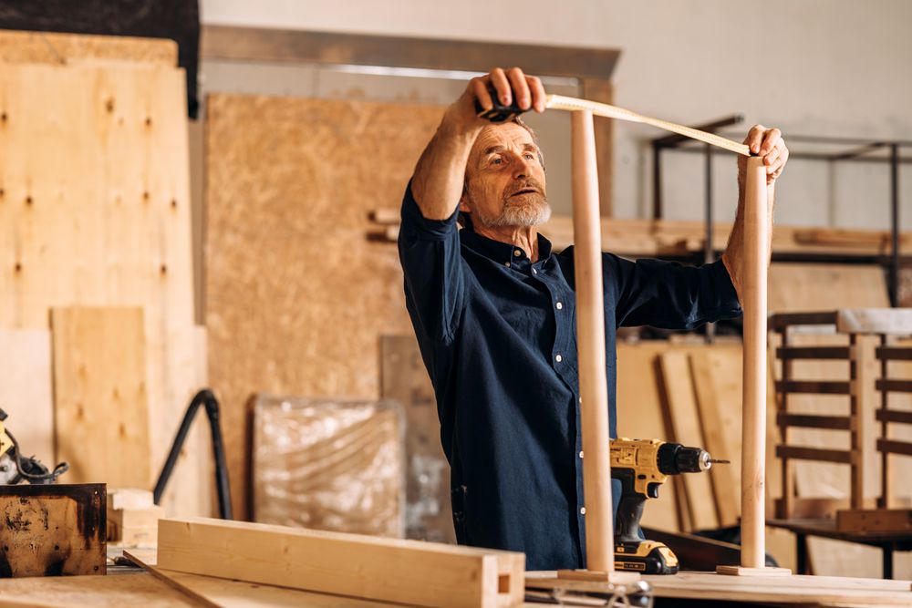 Bearded male with measuring table and furniture in shop