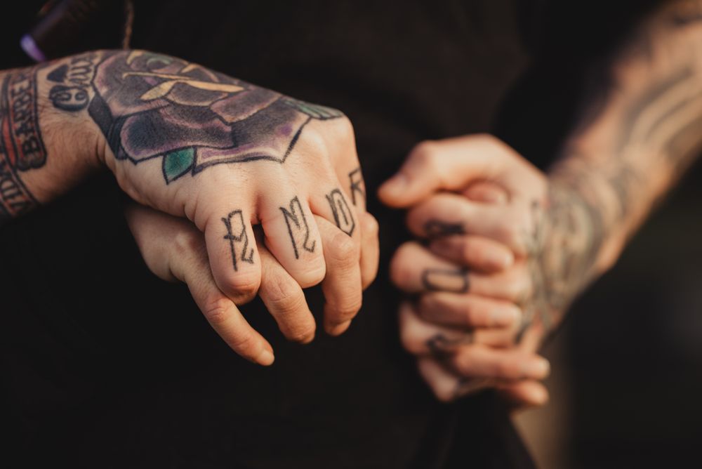 Man in tattoos holding hands of woman