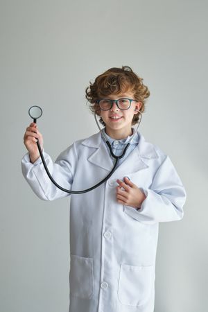 Content boy in medical robe and eyewear with stethoscope