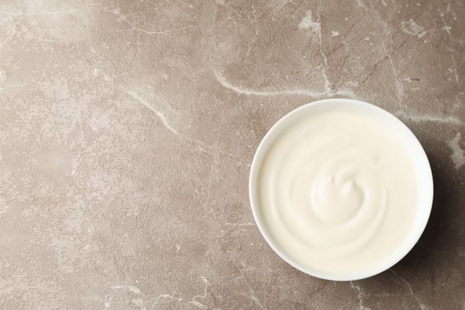 Bowl of sour cream yogurt on grey background