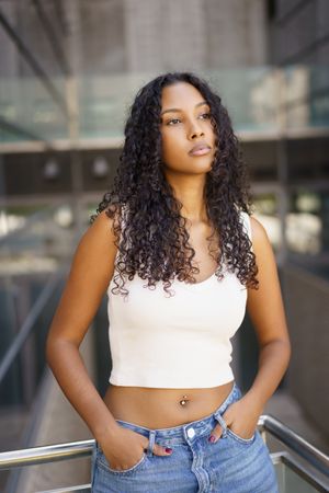 A Confident Young Woman Posing Gracefully in a Modern Urban Setting Under Bright Daylight