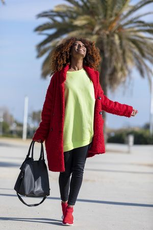 Female walking happily on street with palm trees on sunny day