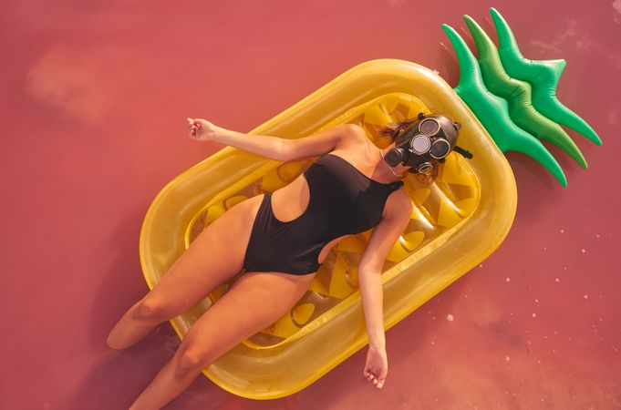 Woman lying on air mattress in pink lake water