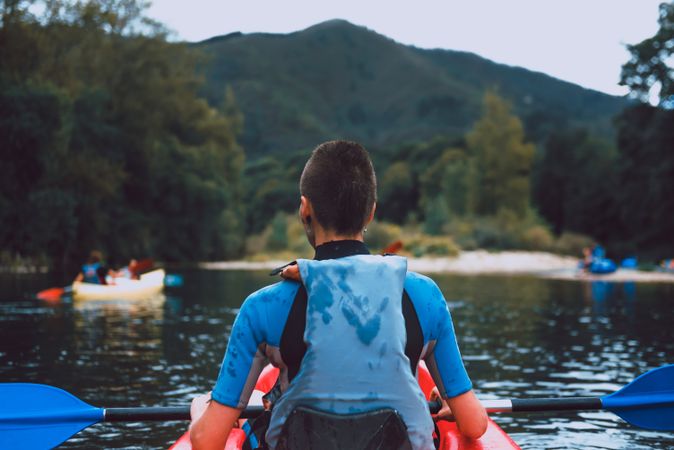 Female kayaking with paddle in raised hands