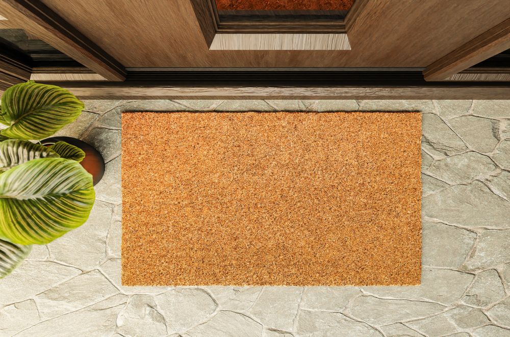 Overhead of blank doormat on the porch at the front door.