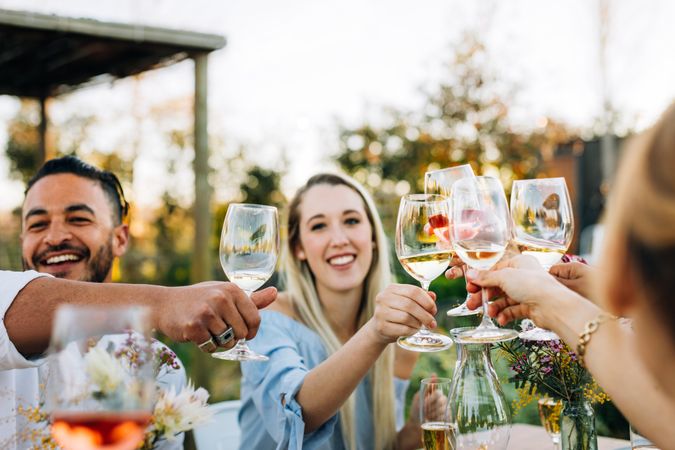 Young people toasting wine glasses over dinner table