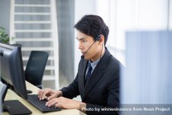 Man at work wearing headset sitting at laptop 5kk9j5