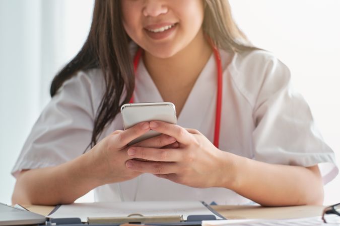 Anonymous doctor browsing smartphone at table