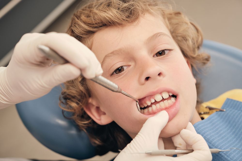 Faceless dentist checking teeth of boy