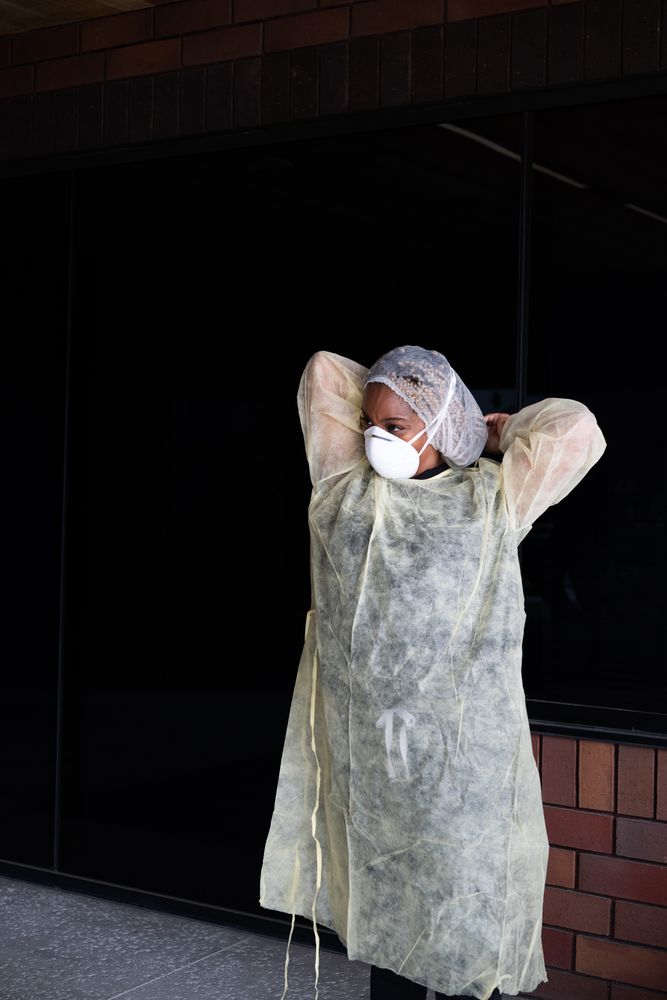 Nurse puts on disposable gown