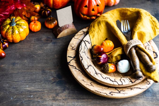 Autumnal table setting with leaves and decorative jack o'lanterns on wooden table