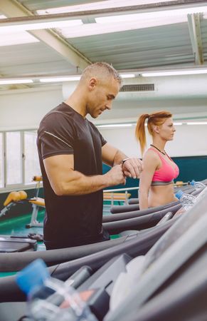 Man checking watch on treadmills in gym