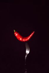 red chili pepper in fork on a dark background