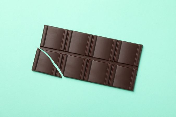 Tasty chocolate bar on mint background. Sweet food
