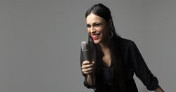 A young female singer, sings with a microphone in her hand while smiling