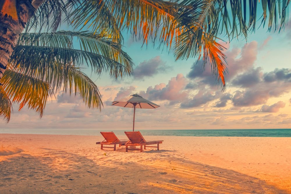Tranquil sunset on the beach with reclining chairs and a parasol