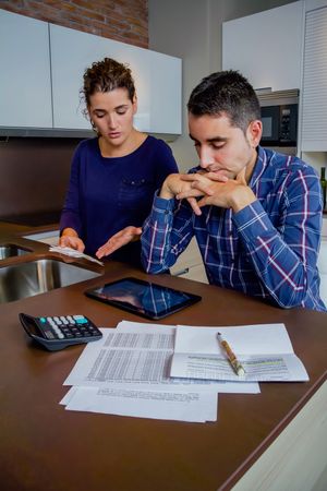 Tense couple working through their bills together in the kitchen