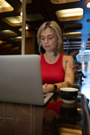 Tattooed young woman working on her laptop in a coffee shop