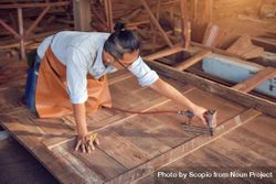 Carpenter drilling a screw into a wooden plank 0VJ6O0