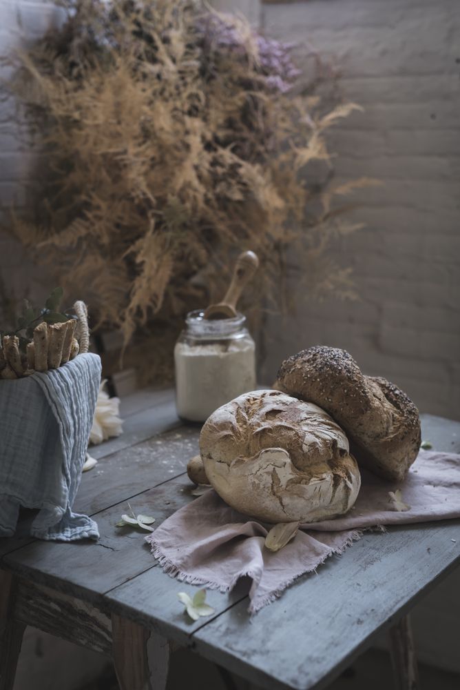 Fresh bread on served table and bunch of dry plant hanging on thread