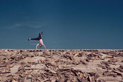 Unrecognizable man performing handstand element of freestyle dance on roof