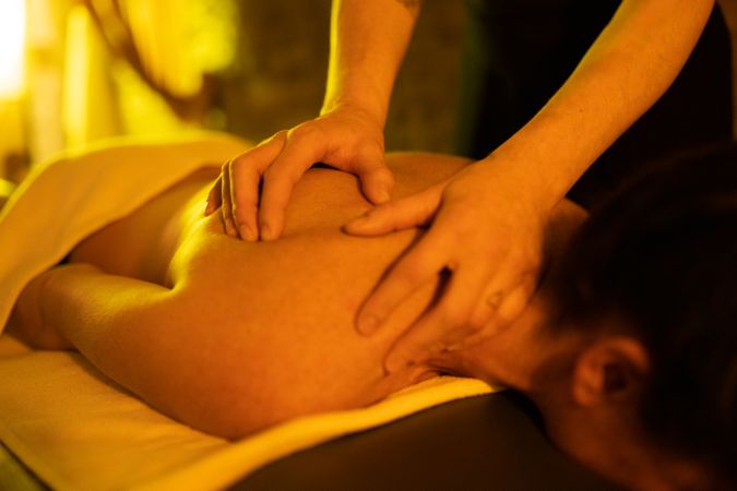Close of up masseuse kneading client’s back