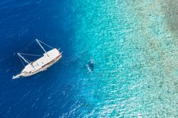 Aerial shot of boat with people swimming in tropical waters